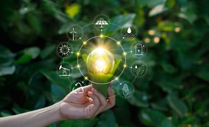 Hand,Holding,Light,Bulb,Against,Nature,On,Green,Leaf,With