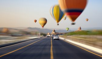 Hot air balloons flies above road in Kapadokya, Turke