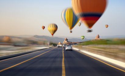 Hot air balloons flies above road in Kapadokya, Turke