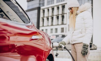 Woman charging red electro car, in winter time